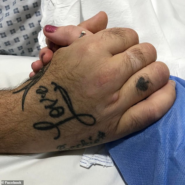 He was waiting to get his second jab when he caught the deadly virus, was placed in an induced coma by doctors after his health quickly deteriorated. His wife holds her husbands hand whilst he is Guy’s and St Thomas’ Hospital in London (pictured)